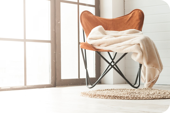 orange lounge chair with a beige blanket on the side in a light modern living room
